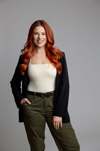 Red-haired woman standing with hands on hips in confident studio portrait. Photograph by Yucaipa branding photographer Kaitlyn Dawn Photography.