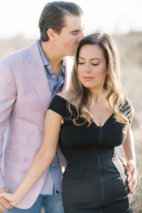 Close-up of a couple from the Parker family in Las Vegas, with the man kissing the woman’s forehead as they stand in a sunlit desert setting during a romantic family photography session.