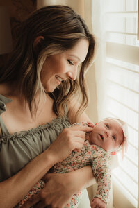 a new mother cuddles her baby during her newborn session with shelly voss photography in dallas,texas