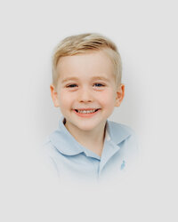 Young boy smiles for the camera during heirloom portrait session with Worth Capturing
