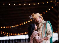 groom smiling at his bride inside barn.