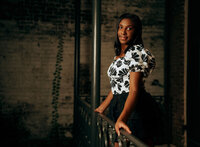 Senior portrait in downtown Mobile, Alabama — leaning against a black wrought-iron railing in a
black top and floral skirt.