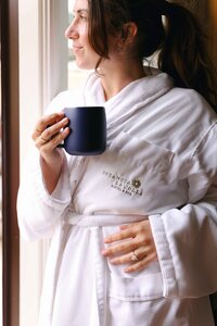 Guest in an Estancia La Jolla robe with morning coffee by the window