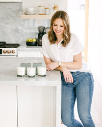 Personal brand photography of a woman entrepreneur in a modern kitchen with styled product details