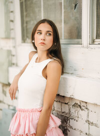 Senior portrait in downtown Foley, Alabama — waist-up leaning on the windowsill, looking off
into the distance.