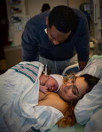 a new dad looks down at his wife holding their new baby