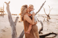Folly Beach Maternity Photographer -- Pregnant woman poses for Maternity Photos at the Lighthouse Inlet Heritage Preserve on Folly Beach with iconic views of the Morris Island Lighthouse in the distance.