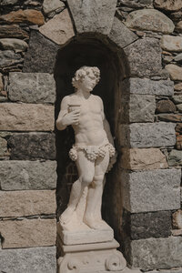 Statue de pierre classique nichée dans une alcove voûtée en pierres des champs au Château St-Agnès, détail architectural du domaine