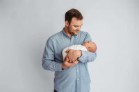 Newborn Pictures in Charleston - Father embraces her newborn baby during Newborn Pictures at Holy City Babies Newborn Photography Studio in Charleston, SC.
