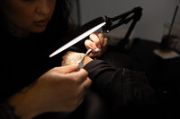 Brow artist concentrating under magnifying light during studio session. Photograph by Yucaipa branding photographer Kaitlyn Dawn Photography.