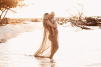 Folly Beach Maternity Photographer -- Pregnant woman poses for Maternity Photos at the Lighthouse Inlet Heritage Preserve on Folly Beach with iconic views of the Morris Island Lighthouse in the distance.