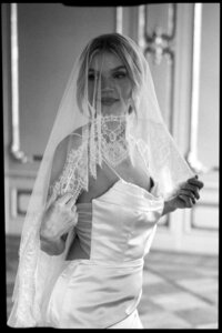 Portrait de mariée sous son voile de dentelle, collier orné et robe bustier satinée, lumière douce en noir et blanc au Fairmont Le Reine Elizabeth, Montréal