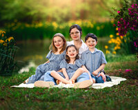 Mother and children smiling together on a blanket surrounded by spring blooms