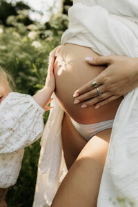 Big sister with her hand on belly during a maternity session in Christchurch