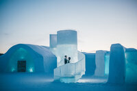 A couple poses on the steps of Icehotel after their weddins.