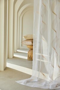 Arched hallway styled with sheer curtains and decorative pillows on a wood stool