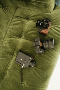 Wedding photography and videography camera gear on a green velvet couch