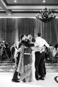 Group of people sharing a heartfelt hug on a dance floor.