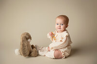 Six month old girl sitting in front of a stuffed bunny for her milestone session at Jennifer Brandes Photography near Mankato, Minnesota.
