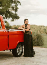 Senior portrait at Triple T Farms in Fruitdale, Alabama — standing beside a classic red truck in a
black lace dress.