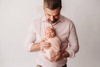 Father holds his newborn daughter for Newborn Portraits at Holy City Babies Portrait Studio in Charleston, SC.