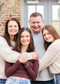 Family portrait session—smiling family of four close together in a greenhouse (Missouri Botanical Garden)