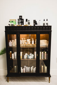 wooden and glass cabinet filled with hair care products