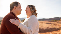 Couple smiling face-to-face at golden hour during their desert adventure session