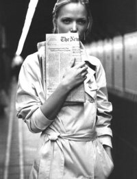 Black and white photo of woman holding the new york times in front of her face
