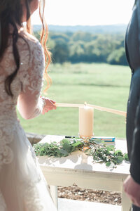Close up of Bride and Groom lighting unity candle during ceremony