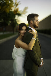 Bride embracing groom during golden hour wedding portraits in cityscape background.