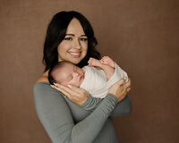 Mother holding her sleeping newborn baby during a studio newborn portrait session with newborn photographer Kaitlyn Dawn Photography.