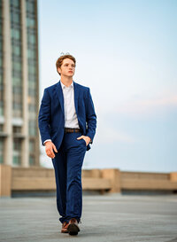 Senior portrait in downtown Mobile, Alabama— walking in a blue suit on top of a parking garage.