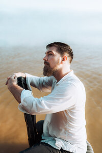 Creative portrait of an artist posed against a light studio backdrop.