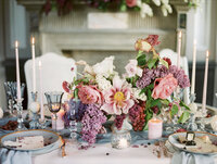 close-up of romantic wedding table with floral centerpiece, blue goblets, candles, and layered textures