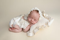 Baby girl posed on a soft neutral cream pillow during her newborn session in South Central Minnesota with Jennifer Brandes Photography.