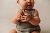 Charleston Baby Milestone Photographer - Baby holds a wooden toy during his Milestone Portrait Session at Holy City Babies Portrait Studio in Charleston, SC.