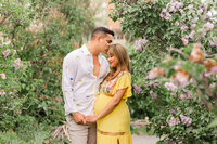Colorado maternity photo—expecting couple holding baby bump in a garden with blooming flowers