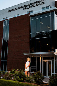 College senior wearing graduation attire at sunset with off camera flash