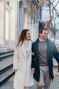 Couples walks down a sidwalk in Soho and smills into the street