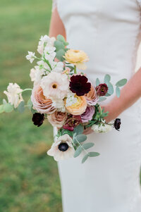 Bride holds bouquet of white and yellow flowers