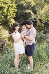 Toronto family photographer captures parents and young baby daughter in lush park near Leaside Toronto on a warm fall evening.