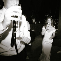 Bride and guest holding drinks at nighttime wedding celebration