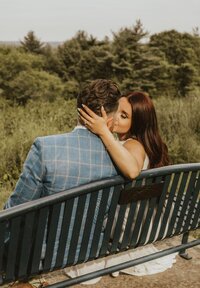 bride and groom sitting on bench kissing
