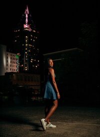 Senior portrait in downtown Mobile, Alabama — back to the camera with her head turned, RSA
Tower lit behind her.