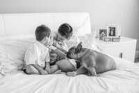 St. Johns newborn capturing a black and white in-home of siblings huddled around their baby sister, the family dog joining in to welcome the newest member. (Photographed by Nature's Child Photography)