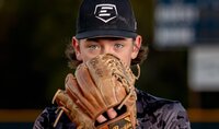 Ponte Vedra portrait session capturing a determined tween baseball player in O’Fallon, Illinois peering over his well-used glove, eyes sharp and focused during a dramatic sunset sports session.
