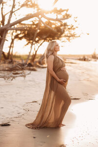 Folly Beach Maternity Photographer -- Pregnant woman poses for Maternity Photos at the Lighthouse Inlet Heritage Preserve on Folly Beach with iconic views of the Morris Island Lighthouse in the distance.