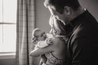a new mom and dad smile at their new baby boy during their newborn session with shelly voss.