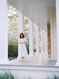 Pregnant woman walking barefoot on a front porch of the house
